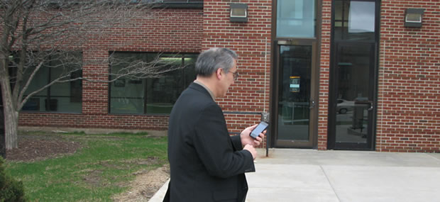 A man looks at his smartphone outside of a building entrance.