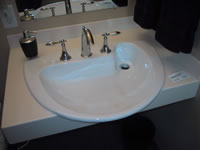 This photograph shows a close-up of the bathroom sink in the model home. The uniquely designed sink has space beneath for wheelchair accessibility and lever handles for easy manipulation of on-off controls.