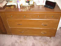 This photograph displays drawer pulls that have been added to the dresser. The Bar Drawer Pulls were added because they are universally designed and easier to use than many other handle or pull designs. They also are relatively large and have an adequate amount of space between the pulls and the drawer, so that the user can easily get his/her hand in between them. They also are useful for arthritic hands and can be accessed easily using an assistive device such as a grabber. The pulls reduce the forces necessary to open and close the drawers.