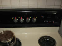 This photograph shows tactile, colored dots that have been strategically placed on the burner knobs. They enable the user to more easily view the stove and oven settings. Bright, yellow dots mark the knob that corresponds with each burner on the stove. Red dots are located at the top of the four burner knobs highlighting the off positions for the burners. The red dots also allow the viewer to gauge how high or low the oven settings are placed relative to the off position. The red dots on the right side of the photograph cover three important stove controls, allowing the user to quickly and easily locate needed switches.